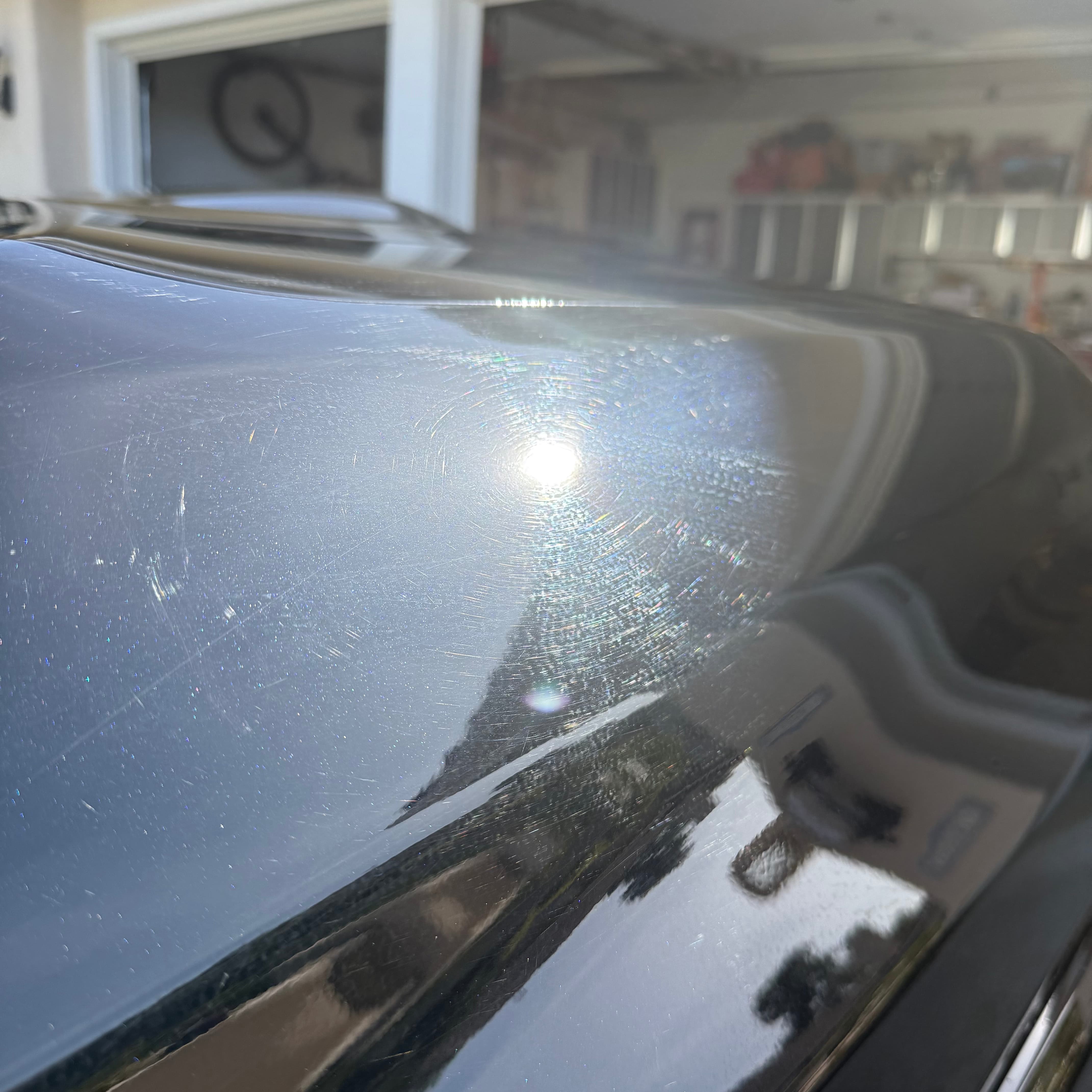 Before: heavy swirl marks under LED light on dark blue BMW hood